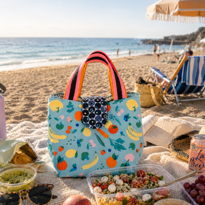 Colorful lunch bag with food and drinks on a sandy beach