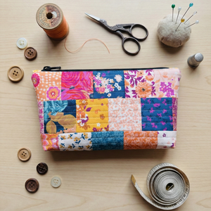 Colorful patchwork pouch with sewing supplies on a wooden surface