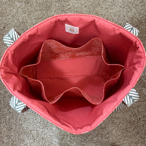 Pink bag with a brand label on a carpeted floor