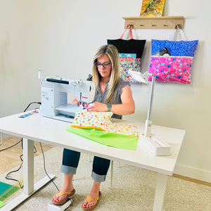 Amanda holding a green dinosaur reading pillow cover with transportation pillow hanging on wall behind her
