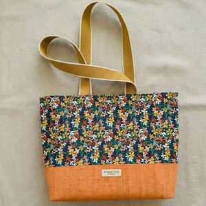 Floral patterned tote bag with a brown base on a beige background