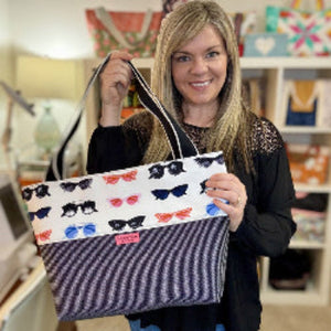 Amanda holding a tote bag with sunglass design in a store setting