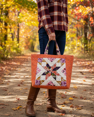 Person holding a floral quilt-style tote bag in an autumn setting