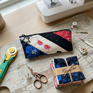 Sewing workspace with a colorful fabric pouch, scissors, and a sewing machine.