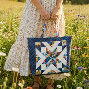 Woman standing in a wildflower field holding the Starry Tote bag