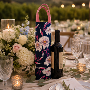 Decorative floral wine tote bag on a table with a bottle of wine, glasses, and flowers.