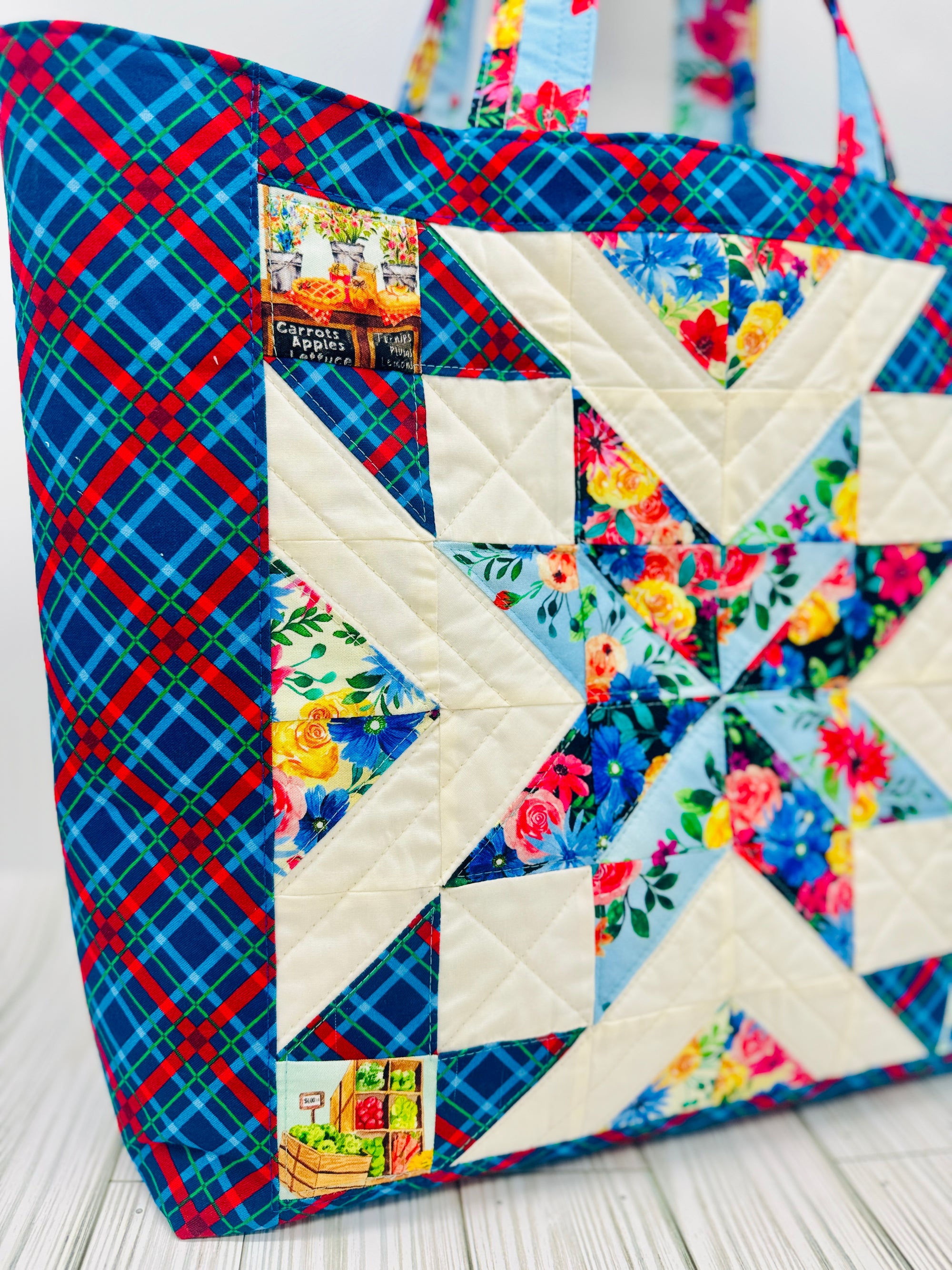 Colorful quilted tote bag featuring a star quilt block pattern with floral and plaid fabrics