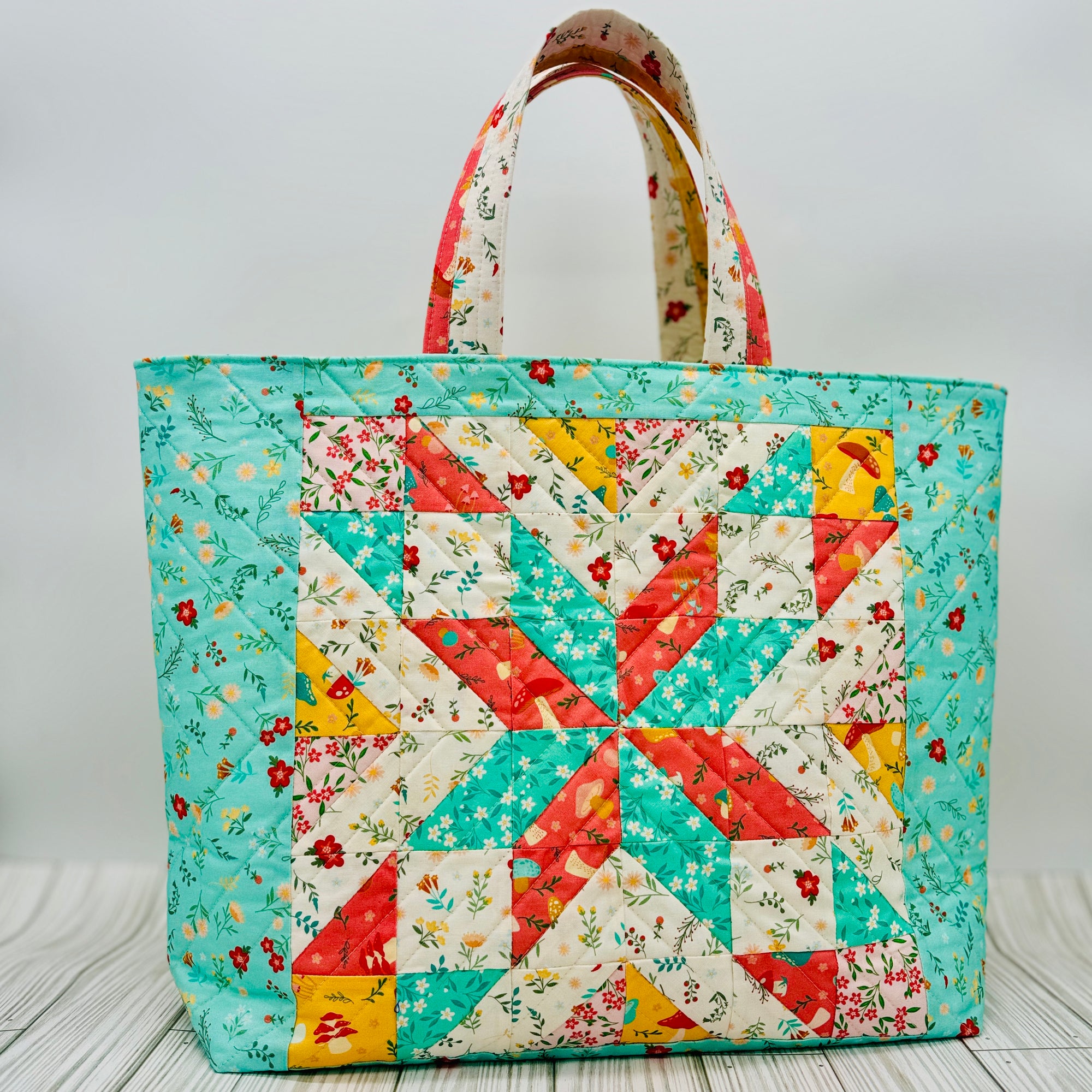 Colorful quilted tote bag featuring a star quilt block pattern with floral fabric