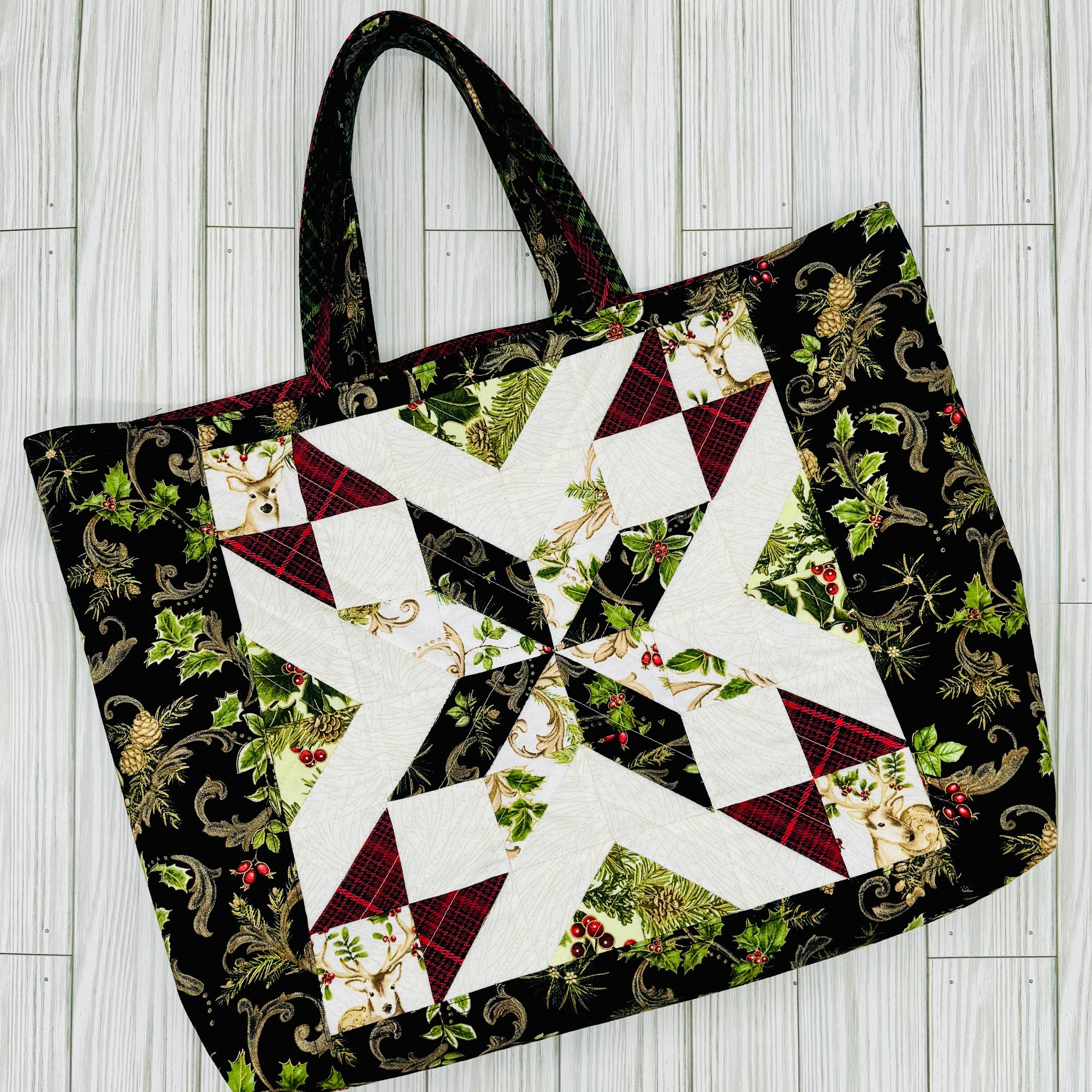 Tote bag featuring a star quilt block pattern with holiday-themed fabric and greenery accents