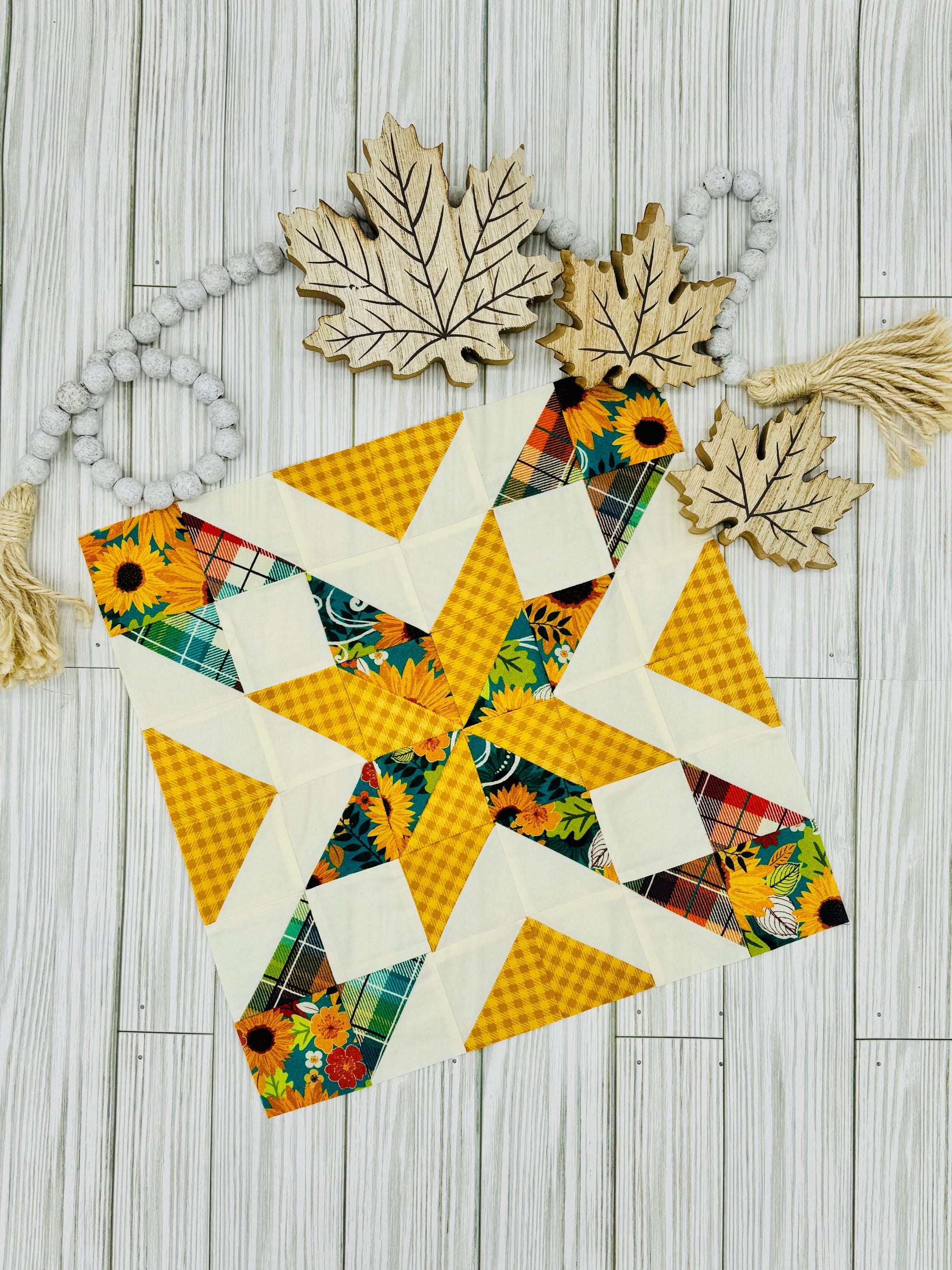 Colorful star quilt block pattern with sunflower and plaid fabrics on a wooden background