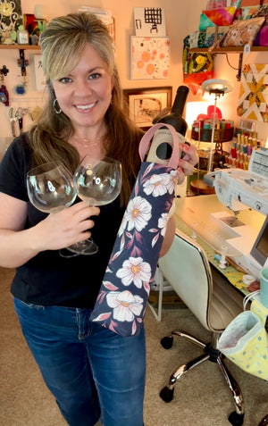 Be Mandy Things grapeful wine bottle tote in floral pattern held by a smiling woman with wine glasses