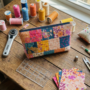 Colorful patchwork pouch on a wooden table with sewing supplies
