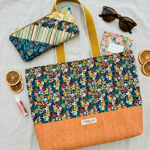 Floral patterned tote bag with a matching pouch and sunglasses on a light background