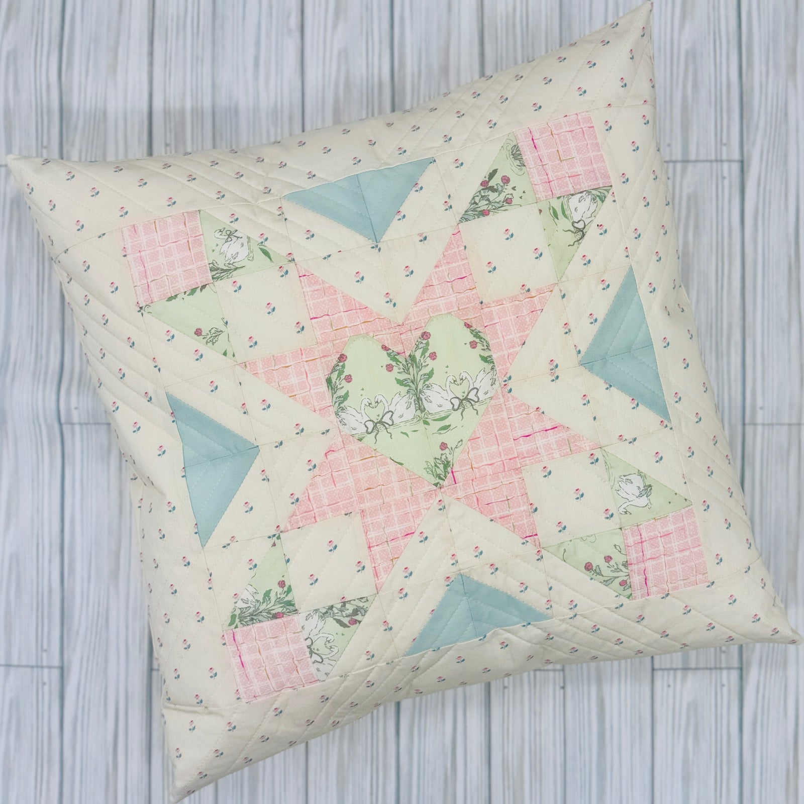 Quilted heart pillow cover with a colorful patchwork design in soft pastel colors